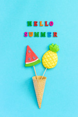 Hello summer colorful text, pineapple and watermelon lollipops in ice cream waffle cone on blue paper background. Concept vacation or holidays Creative Top view Template Greeting card, postcard
