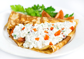 Thin delicious pancake with cottage cheese and tomatoes on white