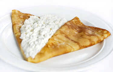 Thin delicious pancake with cottage cheese on white