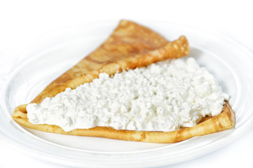 Thin delicious pancake with cottage cheese on white