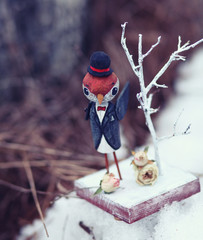 Fun wooden bird sparrow in the hat and dinner jacket with dried rose.