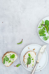 Frisches Brot, mit veganem Frischkäse und Salat auf einem hellen Betonhintergrund