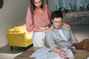 woman standing near man holding cigarette while looking at charts and graphs