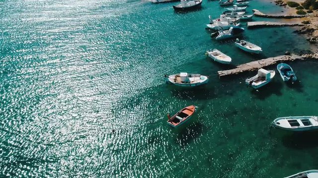 Aerial view of small pier with parked boats on blue water