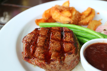 Closed Up Grilled Tenderloin Steak with Blurred Steamed Vegetables and Fried Potatoes in Background