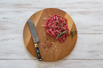 Sliced raw meat on a wooden board. 