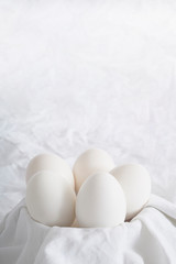 Fototapeta na wymiar Group of chicken eggs in a bowl on white cloth