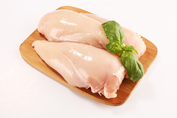 Raw chicken breasts and spices on wooden cutting board, close up