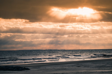 Dramatic sun rays (God rays) coming through the clouds at the beach. Long Beach - Long Island New York. 