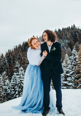 A crazy couple go to the winter pine forest, a woman in a blue wedding dress, a man in a suit