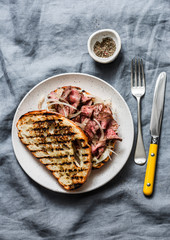 Medium rare beef steak ciabatta sandwiches with homemade mayonnaise mustard sauce on a grey background, top view. Copy space