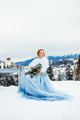 A elegant girl in a blue dress with bouquet in hands sitting on a chair against a background of...