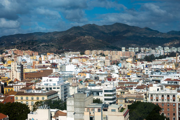 Fototapeta na wymiar View of the Spanish city of Malaga from a height. Residential buildings, mountains, sights on the background of a cloudy sky.