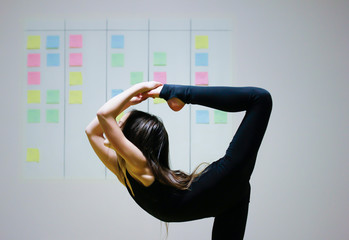 Girl symbolizes flexibility of agile project management approach: she is doing gymnastics element on the background of scrum task board