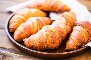 Fresh croisssants buns heap in wooden tray, french croissants, fresh crusty breakfast croissants buns