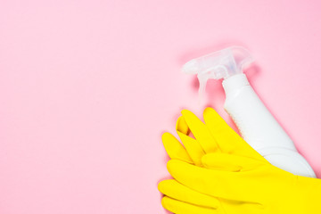 Cleaning spray and gloves on pink background.