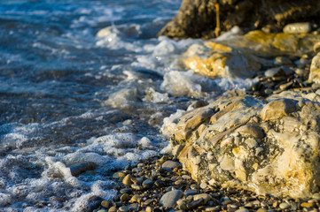pebble stones on the sea beach, the rolling waves of the sea with foam