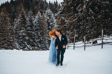 Fototapeta na wymiar Funny couple walking in the snowy forest in the mountains