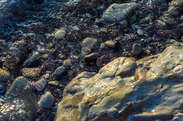 pebble stones on the sea beach, the rolling waves of the sea with foam