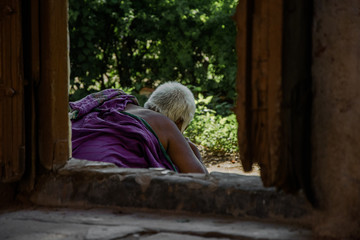 Fototapeta na wymiar Mujer canosa a través de una ventana de madera en la India, de espaldas