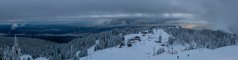 Fototapeta na wymiar Panoramic view of Grouse Mountain Ski Resort during a cloudy winter sunset. Taken in North Vancouver, British Columbia, Canada.