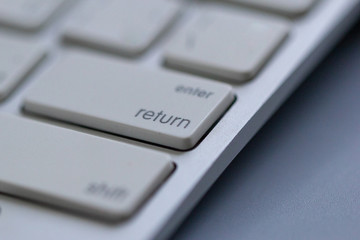 Wireless keyboard on gray background. Which is a close-up angle focusing on the Return or Enter button