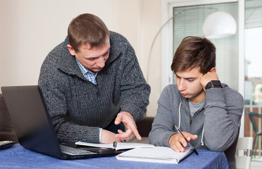 Father checks school assignments teenager son