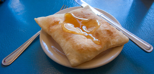 Naklejka premium Sopapilla. Zbliżenie, kolorowe zdjęcie sopapilla z restauracji w Santa Fe, Nowy Meksyk, USA. Jest to południowo-zachodni deser, który jest pustym kwadratowym kawałkiem smażonego ciasta z miodem na wierzchu