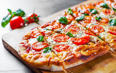 oval Pizza with Mozzarella cheese, Tomatoes, pepper, Spices and Fresh Basil. Italian pizza. Pizza Margherita or Margarita on wooden table background