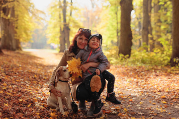 Fototapeta premium Mid age woman with little girl and beagle in the autumn park.