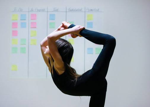 Girl Symbolizes Flexibility Of Agile Project Management Approach: She Is Doing Gymnastics Element On The Background Of Scrum Task Board