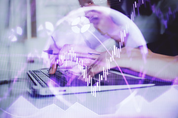 Hands typing on laptop. Business and Financial concept. Double exposure of stock market charts.