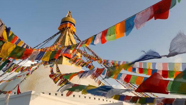 Colorful prayer flags flying in the wind at Boudhanath Stupa, Holy Pagoda, symbol of Nepal and Kathmandu with golgen Buddha's Eyes. Sunset ligth.