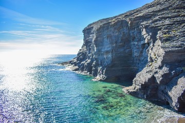 Fototapeta na wymiar Grey cliffs rise sharply from the clear water of the mediterranean along the rocky coastline of southern spain. 