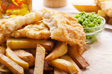 Traditional British street food fish and chips with mushy peas on parchment paper