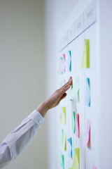 Hand of woman sticks task sticker onto the scrum task board - obrazy, fototapety, plakaty