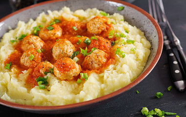Meatballs in tomato sauce with mashed potatoes in bowl.
