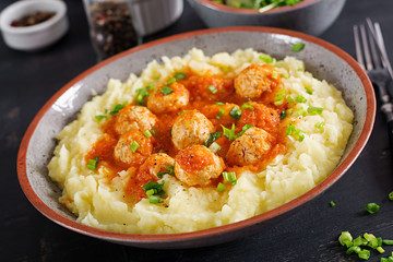 Meatballs in tomato sauce with mashed potatoes in bowl.