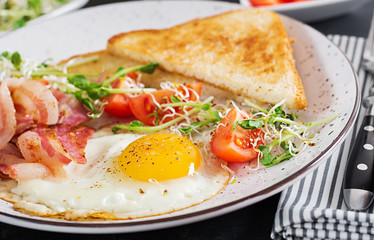 English breakfast - toast, egg, bacon and tomatoes and microgreens salad.