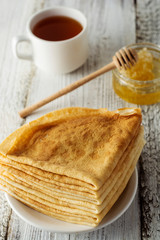 Pancakes. Thin pancakes. Russian bliny. Healthy tasty breakfast - pancakes, a cup of tea and honey.