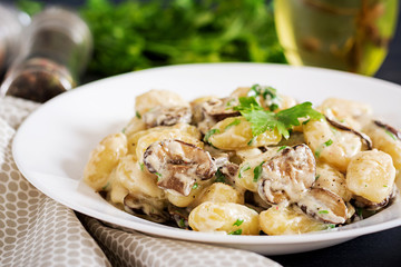 Gnocchi with a mushroom cream sauce and parsley  in bowl on a dark background