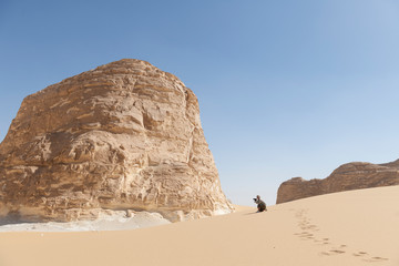 Fototapeta na wymiar Female tourist taking photos on a sanddune in the El Aqabat desert in the White Desert National Park