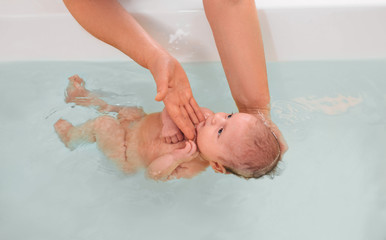 Swimming instructor teaches infant baby to swim. Aquatic therapy for infant baby