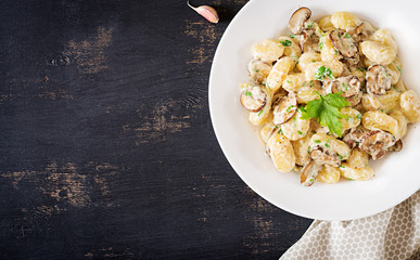 Gnocchi with a mushroom cream sauce and parsley  in bowl on a dark background. Top view