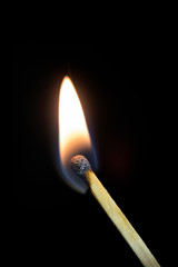 Bright burning match on a black background, shot close-up.