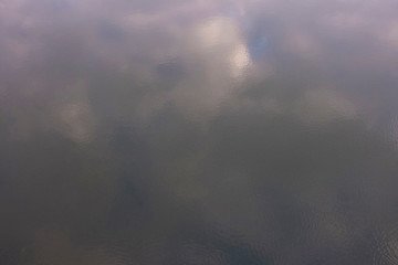 Blurred reflection of clouds on the surface of the water with light ripples.