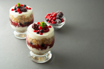 Overnight oats, muesli with berries. Healthy breakfast in glass over grey background. Tasty oatmeals with yogurt.