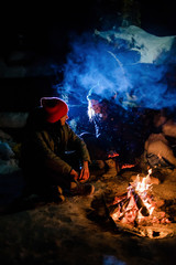 A couple sitting near the fire and exhale blue smoke.  Romantic night