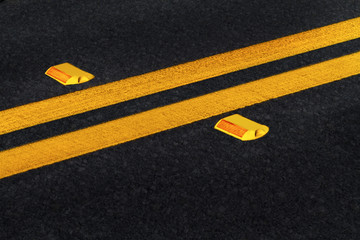 Double yellow lines on black asphalt road with reflectors