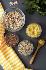 Various uncooked cereals. Different types of groats in bowls on gray background, top view, close up. Healthy nutrition food